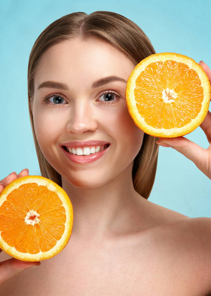 Pretty charming joyful attractive cheerful funny comic positive nude natural pure girl having two pieces of orange, on blue background. isolated on beige background with copy space for advertisement. Skincare. Vitamin C. Blonde woman - Foto, Imagem