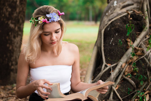 Genç bir kadın parkta kitap okuyor. - Fotoğraf, Görsel
