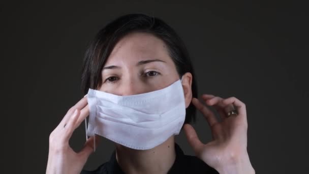 Retrato de uma mulher caucasiana vestindo uma máscara médica branca para proteção contra doenças contagiosas, coronavírus
 - Filmagem, Vídeo