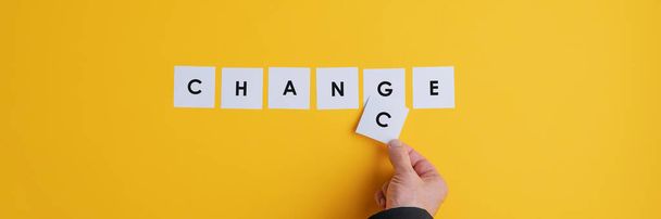 Hand of a businessman changing the word Change into Chance. Conceptual image of business opportunity. Wide view image over yellow background. - Photo, image