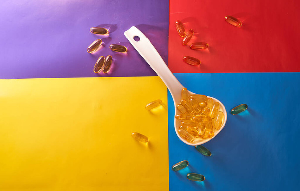 žluté pilulky v bílé velké lžíce na barevném pozadí - Fotografie, Obrázek