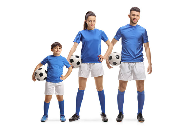 Full length portrait of a young man, woman and a boy in sports jersey holding soccer balls isolated on white background - Photo, Image
