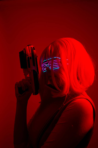 Girl with blaster in the futuristic battle. Concept virtual reality, cyber game. - Foto, Bild