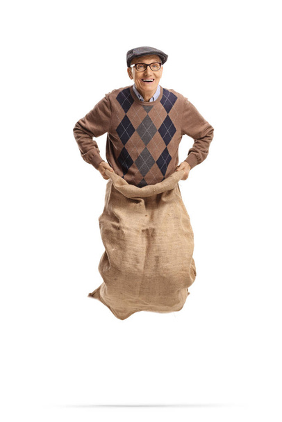 Happy elderly man jumping inside a sack isolated on white background - 写真・画像
