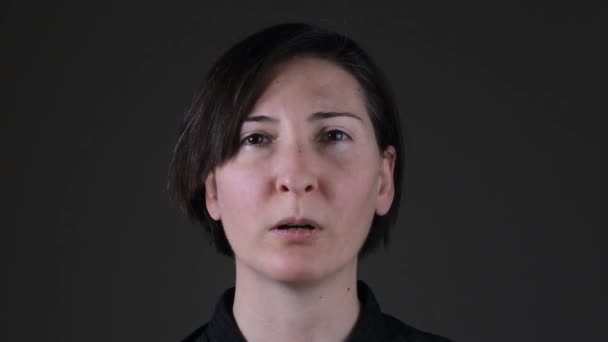 Porträt einer kaukasischen Frau, die vor grauem Hintergrund atmet - Filmmaterial, Video