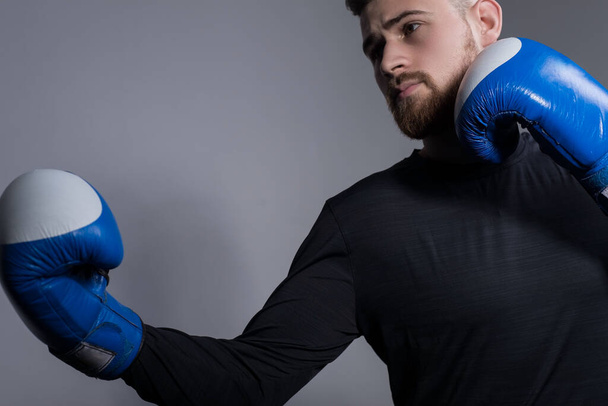 Close-up of a bearded aggressive athlete in boxing gloves, getting ready, stabs. On a gray background. Boxing, MMA, martial arts, sports and health. Majority athletes, scream. Conor Margregor. Boxer, looks like a MacGregor. Active lifestyle. Traffic. - Fotoğraf, Görsel
