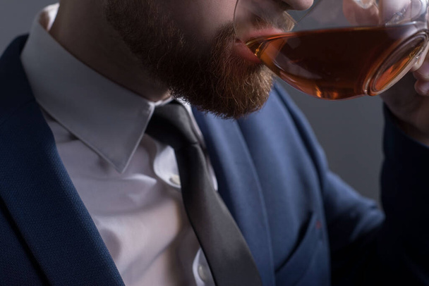 close-up, on a clearance on a white background, silhouette of a bearded handsome guy drinking tea from a transparent cup. Promotional photo of black tea. Coffee break man. Lunch. - Fotó, kép