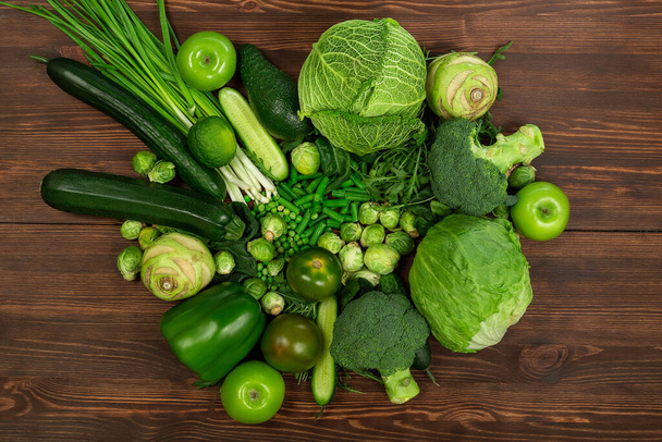 Collection of green vegetables produce on dark background, broccolini, avocado, squash, chilli, grapes part of flat lay overhead set - Foto, immagini