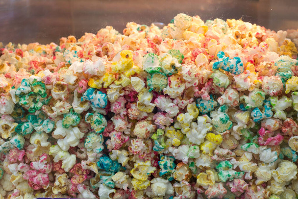Gros plan texture de pop-corn multicolore dans un récipient de cinéma en verre. Popcorn avec une variété de couleurs et de saveurs
. - Photo, image