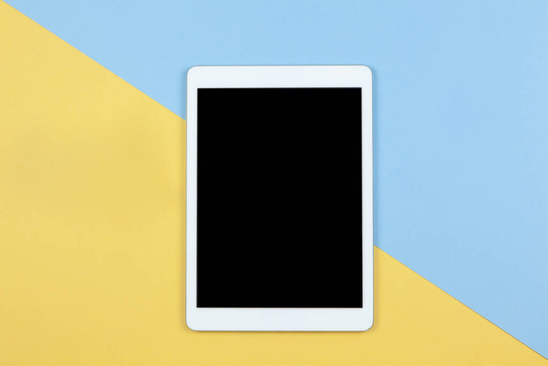 Tablet with empty screen on yellow and blue background, copy space, flat lay. Working space of freelancer. Freelance, planning of vacation, travel, work from home, using technology concept. Horizontal - Photo, Image