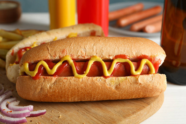 Ízletes hot dog, sör és mártások fehér fa háttér - Fotó, kép