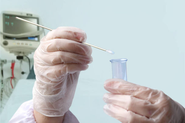 doctor holds in his hand a laboratory test tube with liquid, does an analysis on COVID-19 against the background of a ventilator, the creation of a vaccine for the SARS-CoV-2 virus, coronavirus, flu - Foto, afbeelding