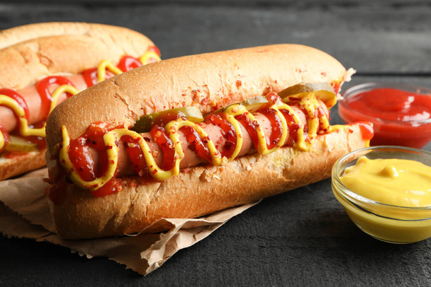 Tasty hot dogs and sauces on wooden background - Photo, Image