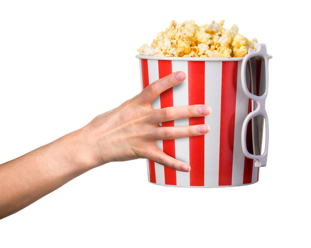 Woman hand holding striped bucket with popcorn and 3D glasses isolated on white - Valokuva, kuva