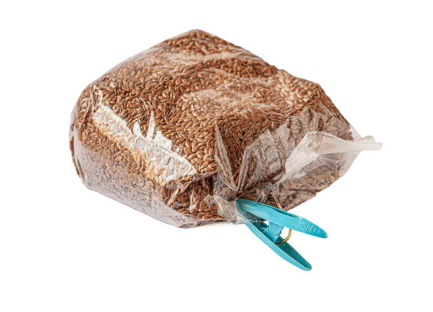 flax seeds in a plastic bag closed with a clothespin isolated on white - Photo, Image