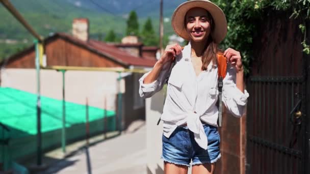 joyful young girl tourist in white shirt and straw hat walking on ancient street - Felvétel, videó