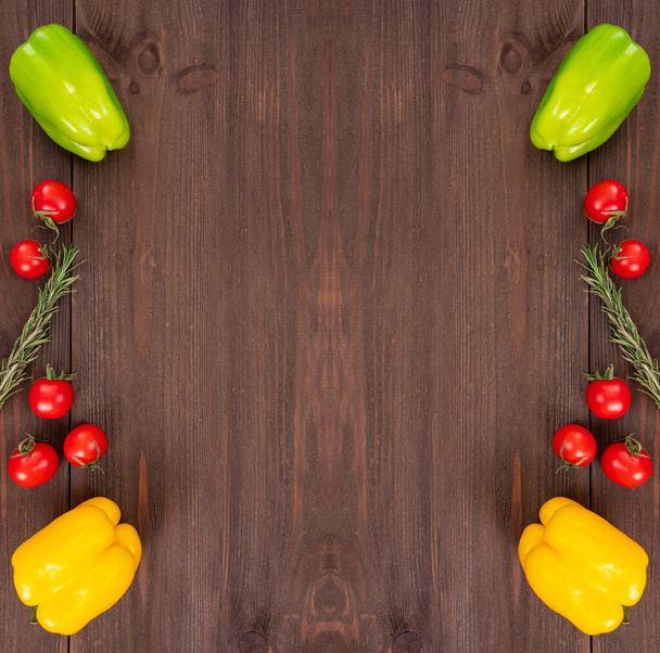 Kiraz rengi domatesler, farklı renkte dolmalık biberler ve ahşap desenli arka planda biberiye bitkisi. Taze sebzeler, kopyalama alanı olan şablon - Fotoğraf, Görsel