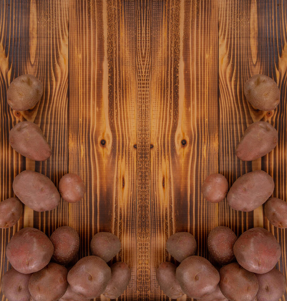 Συλλεχθέντες σωροί από κόκκινες πατάτες σε ξύλινο ανάγλυφο φόντο. Φρέσκα λαχανικά, πάνω όψη με χώρο αντιγραφής - Φωτογραφία, εικόνα