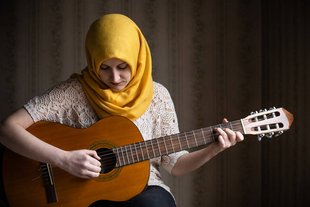 Portrait of cute modern muslim woman playing guitar. Diversity concept - Photo, Image