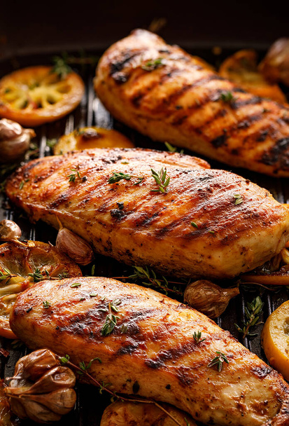 Petti di pollo alla griglia con fette di timo, aglio e limone su una padella da vicino, vista dall'alto
 - Foto, immagini