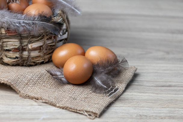 Fresh natural chicken eggs on a brown background with a basket - 写真・画像