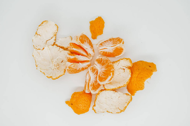 Trozos de jugosa mandarina desmontados en trozos de primer plano. Se encuentran en una superficie clara. Vista desde arriba
 - Foto, imagen