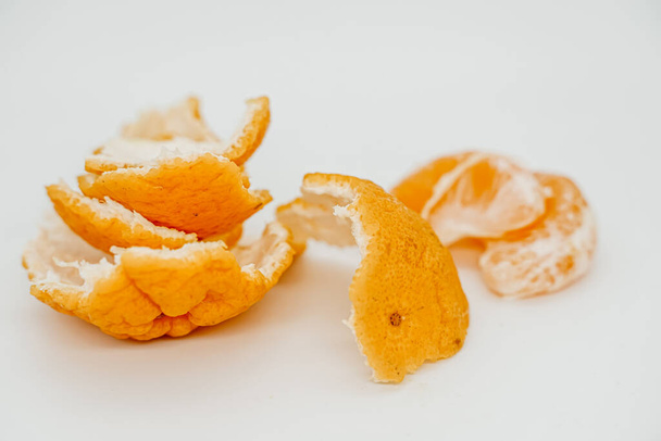 Trozos de jugosa mandarina desmontados en trozos de primer plano. Se encuentran en una superficie clara. Vista lateral
 - Foto, imagen