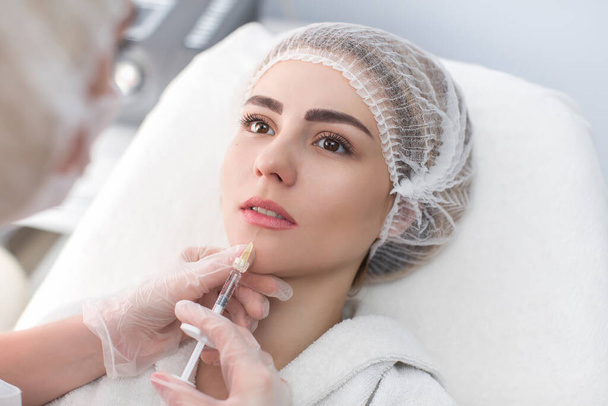 Hands of cosmetologist making injection in face, lips. Young woman gets beauty facial injections in salon. Face aging, rejuvenation and hydration procedures. Aesthetic cosmetology - Φωτογραφία, εικόνα