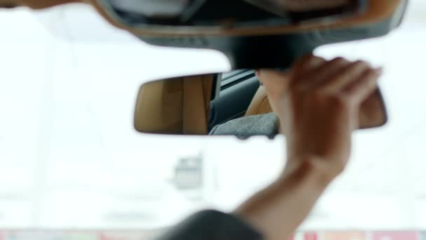 Serious woman adjusting rear view mirror. Woman sitting behind steering wheel - Πλάνα, βίντεο