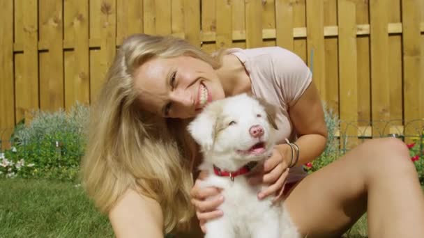 PORTRAIT: Mujer caucásica feliz mascotas peludo perrito y mira a la cámara. - Imágenes, Vídeo