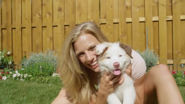 FECHAR-se: Menina caucasiana alegre sorri enquanto segurando um filhote de cachorro branco fofo
. - Filmagem, Vídeo