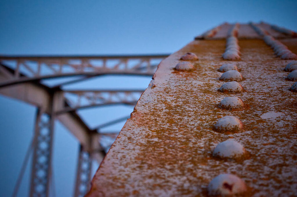 geklonken detail van een roestige beugel van een metalen brug - Foto, afbeelding