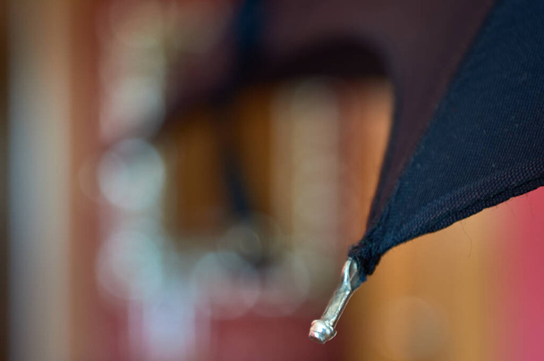 defocused λεπτομέρεια μιας άκρη που κορυφώνεται τις ράβδους ενός κλασικού μαύρη ομπρέλα - Φωτογραφία, εικόνα