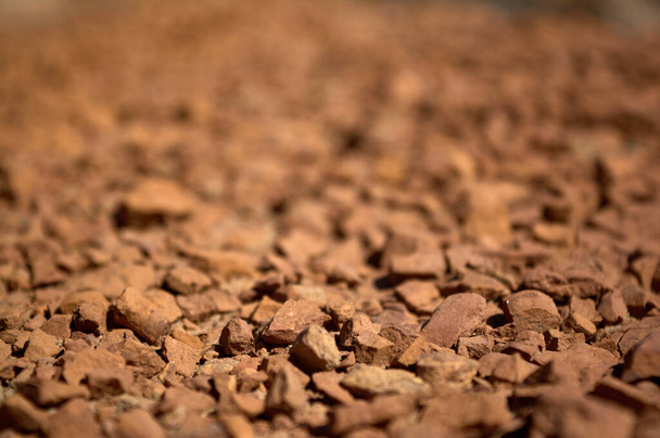 Detalhe desfocado de grupo de pequenas pedras semelhantes a barro avermelhadas em um wadi seco no verão
 - Foto, Imagem