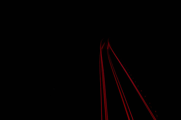 dettaglio di tracce di lampadine posteriori di veicoli che attraversano su una strada di notte
 - Foto, immagini
