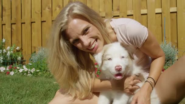 CLOSEアップ: adorableショットのブロンド女の子接吻とともにザ柔らかい白い子犬. - 映像、動画
