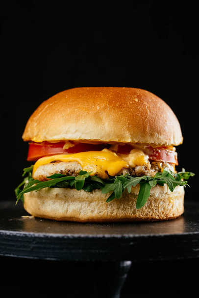 hamburguesa con carne de res, tomates, lechuga fresca y queso sobre fondo de piedra oscura
 - Foto, Imagen
