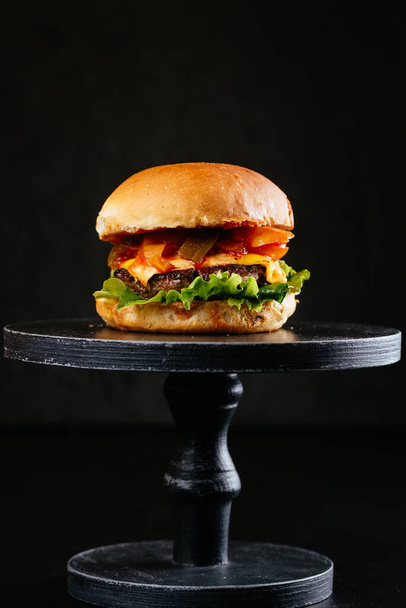 grilled white buns meat burger with cheese, chopped cucumbers and vegetable saute on wooden table background - Fotó, kép