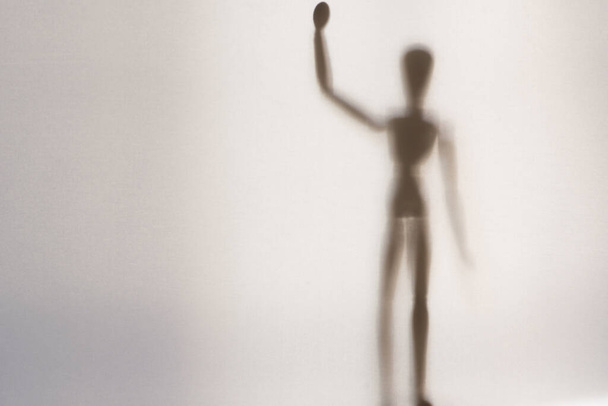 An artist wooden model standing up waving it's hand.  Shot through a semi transparent material. Creating a textured, blurred beautiful still life. - Foto, imagen