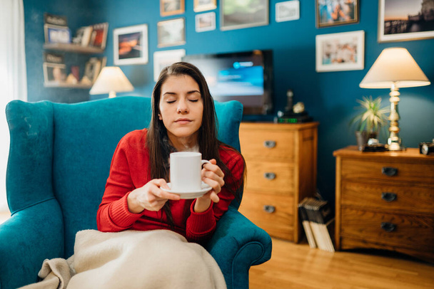 Young woman drinking coffee/tea, spending free time home.Hot beverage for health.Self care,staying home,quarantine.Self-isolation instant coffee.Starting the day,morning ritual.Serene mornings. - Фото, изображение