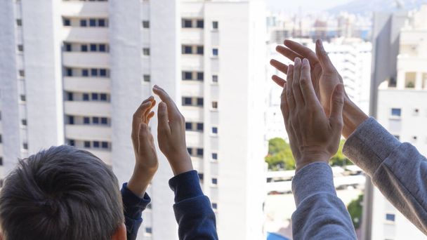 Manos familiares aplaudiendo al personal médico desde su balcón. Personas en España aplaudiendo gratitud en balcones y ventanas en apoyo a trabajadores de la salud, médicos y enfermeras durante la pandemia del Coronavirus
 - Foto, Imagen