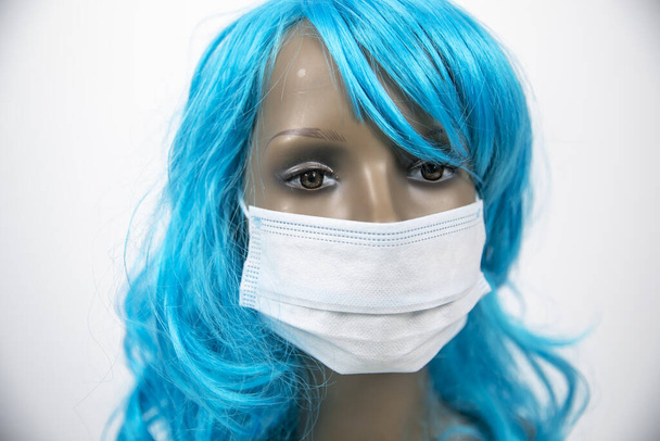 eine Schaufensterpuppe mit blauen Haaren, die zum Schutz vor Viren eine Gesichtsmaske trägt - Foto, Bild