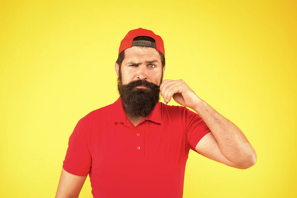 Male beauty tips. serious mature hipster yellow background. bearded man red shirt and cap. Hipster lifestyle. Barber salon and facial hair care. being trendy and brutal. Beard and mustache grooming - Photo, Image
