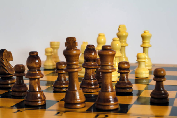 Chess pieces stand on a wooden board close-up isolated on a white background. - Photo, Image
