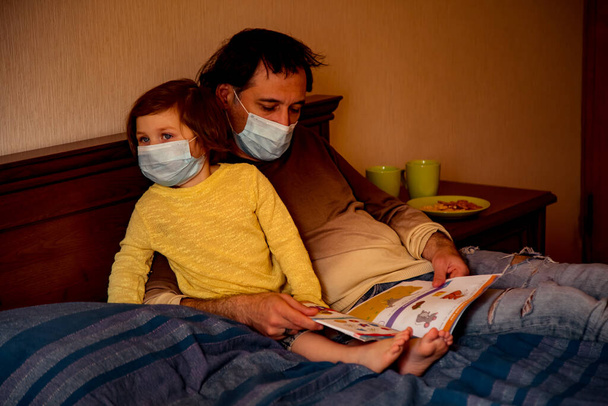 daddy and daughter in medical masks, studying art photography, at home during quarantine, due to the covid-19 pandemic - Photo, Image