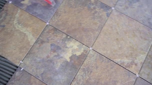 Fésült kerámia csempe a padlón, a mester tesz a csempe a csempe ragasztó alkalmazott egy fésű - Felvétel, videó