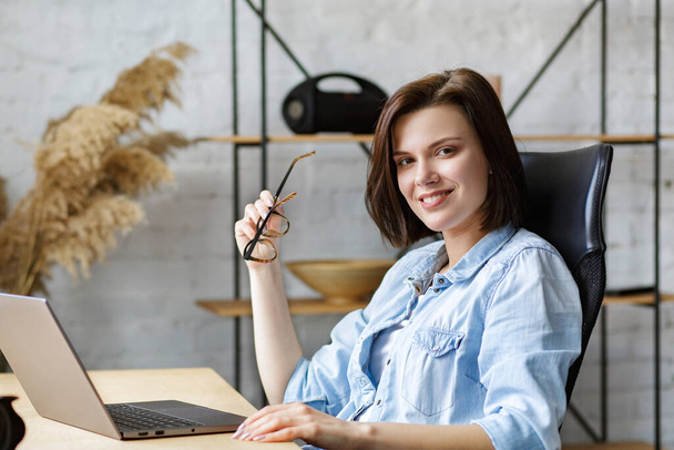 Working from home. Communication online. Portrait of smiling female freelancer using laptop - Zdjęcie, obraz