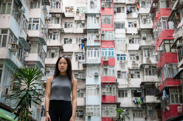 香港で最も人口密度の高い都市の一つである香港島のQuarry Bayにある香港の詰め込まれた公共住宅街の都市景観を探索する中国の女の子. - 写真・画像