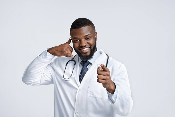 Amigável terapeuta afro-americano indicando aos pacientes, pedindo para chamar
 - Foto, Imagem