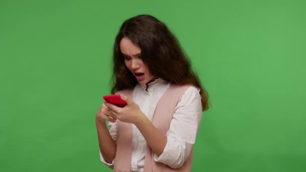 Amazed astonished teenage girl reading message on cell phone, chatting with friends on social networks, surprised by mobile application, using service for online ordering. studio shot, isolated - Záběry, video
